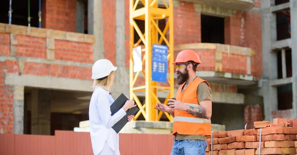 Concepto de comunicación del equipo de construcción. Mujer ingeniero y constructor brutal comunicar el fondo del sitio de construcción. Relaciones entre clientes de la construcción y participantes de la industria de la construcción — Foto de Stock