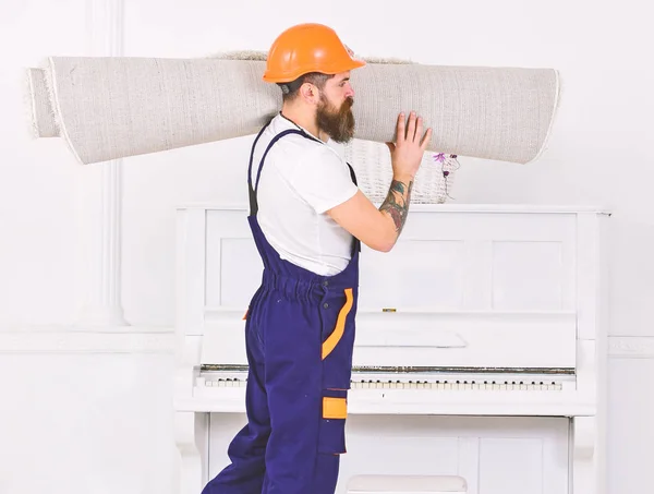 Um tipo com vista lateral a andar com carpete enrolada no ombro. Trabalhador carregando tapete branco. Mudar para um novo lugar — Fotografia de Stock