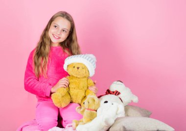 Çocuk küçük kız yumuşak oyuncak oyuncak ayı pembe arka plan ile oynamak. Çocuk küçük kız oyuncak ayı peluş oyuncak tutun. Oyuncak koleksiyonu taşır. Oyuncak ayılar psikolojik refahı artırır. Yumuşaklık anahtardır