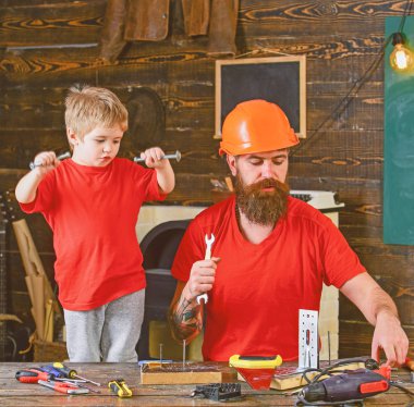 Evlat, çocuk neşeli cıvata veya vida, baba ile handcrafting sırasında eğlenmek tutar. Baba, ana okul atölyesinde farklı araçları kullanmak için kask öğretim oğlu sakallı. Tamirci kavramı