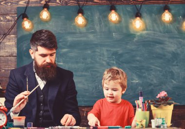 Baba sanatçı oğlu boyamak eğitmektir. Sarışın çocuk çizmek için öğrenme