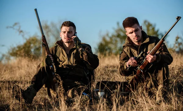 Hunters friends enjoy leisure. Rest for real men concept. Hunters with rifles relaxing in nature environment. Hunting with friends hobby leisure. Hunters satisfied with catch drink warming beverage — Stock Photo, Image