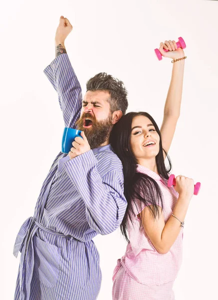 Couple, famille sur des visages somnolents, étirement. Couple amoureux en pyjama, peignoir dos à dos. Fille avec haltère, homme avec tasse de café, isolé sur fond blanc. Concept d'énergie du matin — Photo