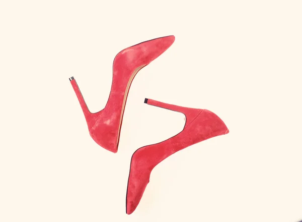 Footwear with thin high heels, stiletto shoes, top view. Pair of fashionable high heeled pump shoes. Shoes made out of red suede on white background, isolated. Luxury footwear concept