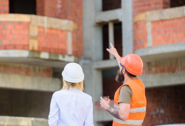 Planı tartışıyoruz. Kadın mühendis ve inşaatçı inşaat alanında iletişim kuruyor. İnşaat müşterileri ve inşaat endüstrisi arasındaki ilişkiler. İnşaat ekibi iletişim konsepti