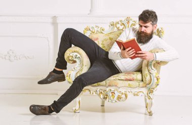 Akıllı kavramı. Sakal ve bıyık oturur koltuk ve okuma kitabı, beyaz duvar arka plan üzerinde olan adam. Maço akıllı kitap ile boş zaman harcıyor. Bilim adamı, Profesör meşgul yüzündeki edebiyat araştırıyor