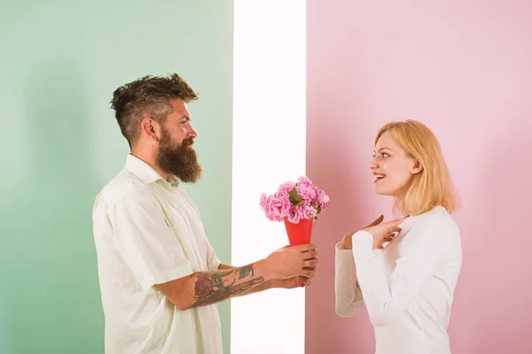 Man with beard congratulates woman birthday anniversary holiday. Hipster bearded give bouquet flowers to girlfriend. Couple date bouquet flowers gift. Gift concept. Couple in love celebrating holiday — Stock Photo, Image