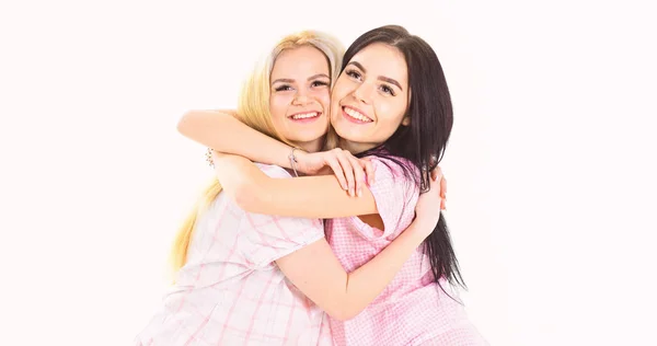 Dos hermosas chicas en abrazos de pijama. Concepto de mejores amigos. Señoras en caras sonrientes se abrazan apretado, fondo blanco, aislado — Foto de Stock