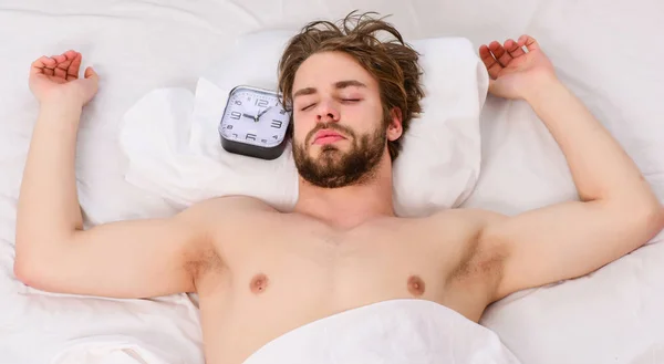 Kép: fiatal férfi az ágyban nyújtás. Közelkép a láb egy ágy a fehér takaró alatt. Az ember reggel ágy. — Stock Fotó