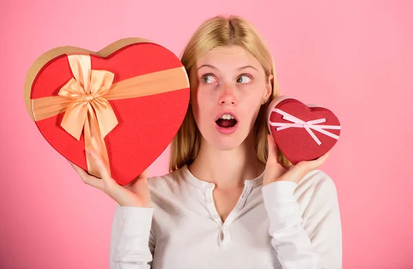 Listen to your heart. Girl decide which gift she like more. Big surprise and small gift. Make choice. Romantic gift for her. Woman hold big and little heart shaped gift boxes. Which one she prefer