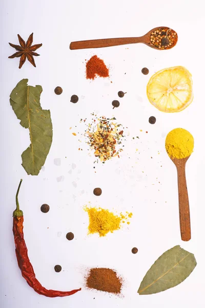 Culinary art concept. Spoons filled with kitchen herbs and spices. Composition of spoons with spices and dried ingredients. Spoons with kitchen herbs, star anise and bay leaf on white background