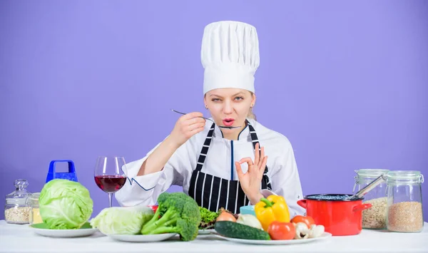 Matlagning hälsosam mat. Färska grönsaker ingredienser för matlagning måltid. Professionella matlagningstips. Kvinna prova smaka mat. Gourmet huvudrätt recept. Läckra recept koncept. Flicka i hatt och förkläde — Stockfoto