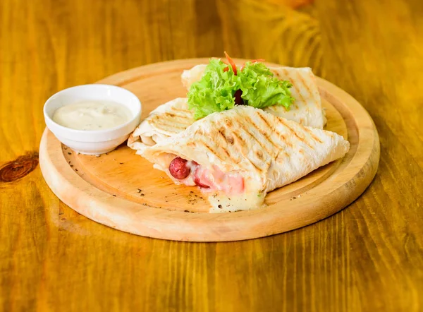 Restaurant repas cuisine traditionnelle. Burrito tortilla servi planche en bois. Concept de restauration. Salade de saucisse de viande farcie au burrito à la lavande et sauce au fromage. Viande enveloppée avec un burrito à la lavande — Photo