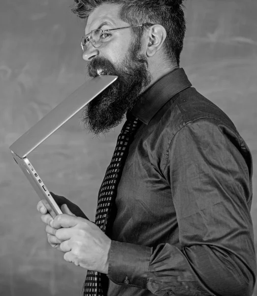 Man hungriga för kunskap. Törst efter kunskap. Lärare skäggig man biter modern laptop chalkboard bakgrund. Hipster lärare bära glasögon och halsduk biter laptop. Han behöver ny information — Stockfoto