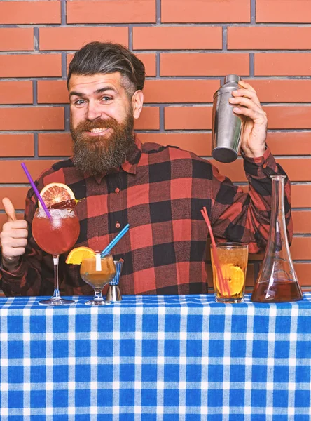 Alkollü içecekler kavramı. Tuğla duvar arka plan üzerinde kareli gömlekli adam içki hazırlar. Barmen uzun sakal ve bıyık ve mutlu yüz tutan shaker, şık saç ile alkollü kokteyl yapar