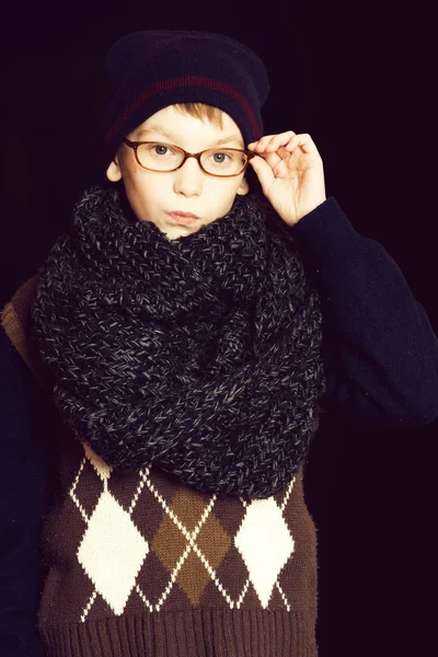 Kleiner ernsthafter Junge oder niedliches Nerd-Kind mit Brille, Hut und modischem Strickschal auf schwarzem Hintergrund — Stockfoto