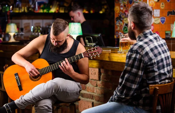 Friday relaxation in bar. Friends relaxing in bar or pub. Hipster brutal bearded spend leisure with friend in bar. Real men leisure. Cheerful friends relax with guitar music. Man play guitar in bar