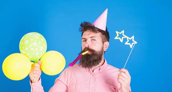 Pembe gömlek ve parti şapkası, parti horn, ıslık giyen sakallı, yakışıklı adam portresi renkli balonlar, kameraya bakıyor tutuyor. İnsanlar, kutlama kavramı — Stok fotoğraf