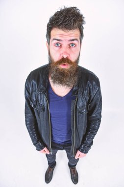 Sakal ve bıyık kameraya bakarak sürpriz yüzünde olan adam. Maço deri ceket, beyaz arka plan giyer. Erkek Giyim ve moda kavramı. Hipster şık kıyafetiyle poz şaşırmış görünüyor