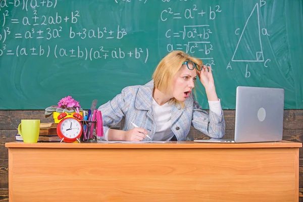 Teacher shocked face keep working after classes. Teacher woman sit table classroom chalkboard background. Work far beyond actual school day. Still working. Teacher busy with paperwork and research — Stock Photo, Image