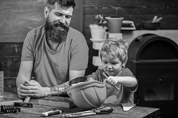 髭の学校ワーク ショップでさまざまなツールを使用するほとんどの息子を教える親の父。父権のコンセプトです。少年、子供保護用のヘルメットと忙しい遊びパパとツールの使い方を学ぶ — ストック写真