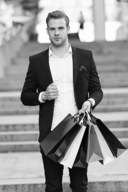 Resmi takım elbise alışveriş torbaları taşımak. Adam taşımak grup alışveriş torbaları. Üstünde siyah Cuma alışveriş karlı fırsatlar. Bir dakika dostum çok kağıt çanta paketleri alışveriş merkezinde alışveriş sonra. Siyah Cuma satış konsepti
