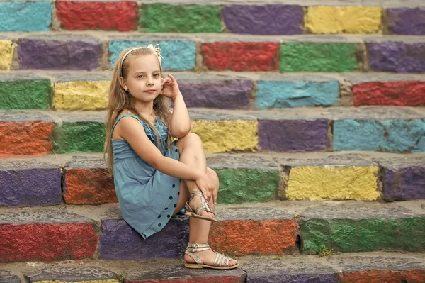 Małe dziecko dziewczyna w niebieskiej sukience na schody kolorowe — Zdjęcie stockowe