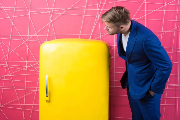 Businessman. curious man. Feel the success. confident businessman in suit. Male formal fashion. sexy man in stylish jacket. Vintage household appliances. Bachelor hungry guy think what eat at fridge