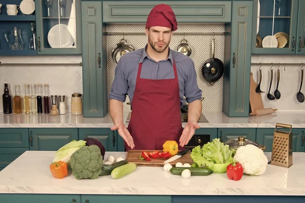 Muž bod na zeleninu na stole. Cook v kuchař klobouk a zástěru v kuchyni. Ingredience pro vaření jídla. Vegetariánské menu a zdravou stravu. Příprava jídla a vaření recepty — Stock fotografie