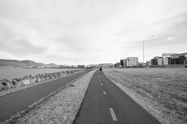 Reykjavik, Islanda - 12 ottobre 2017: strada di viaggio lungo la costa marittima. Strada di campagna su cielo nuvoloso. Miglia di viaggio. Strada del lungomare. La strada si leverà per incontrare colui che la percorre — Foto Stock