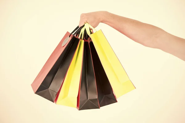 La mano masculina sostiene cinco bolsas de compras. Concepto de compras. Mano sostiene montón de bolsas de compras de colores. Compras el viernes negro. Cliente compró muchos artículos con descuento — Foto de Stock