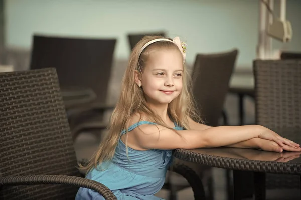 Pequeña niña sonriente en vestido azul cerca de la mesa de café —  Fotos de Stock