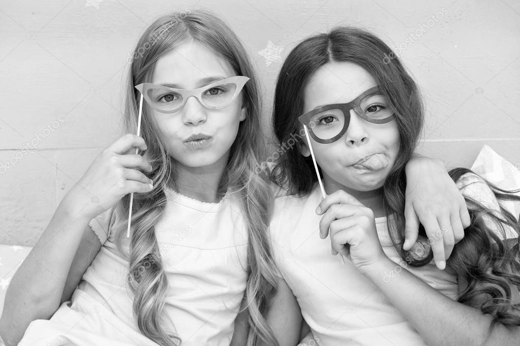 Playful mood. Girls children posing with grimaces photo booth props. Pajamas party concept. Girls friends having fun pajamas party. Friends cute and cheerful posing with eyeglasses accessories