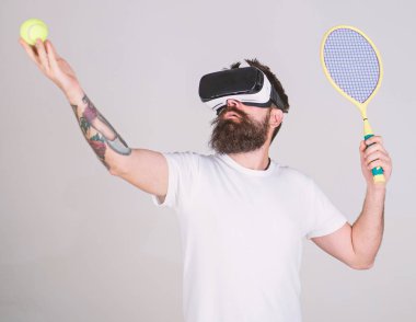 Vr gözlük, gri arka planda sakallı adam. Hipster konsantre yüzündeki spor oyunları için modern teknolojisini kullanıyor. Sanal Tenis kavramı. Vr gözlüklü play tenis raket ve top ile