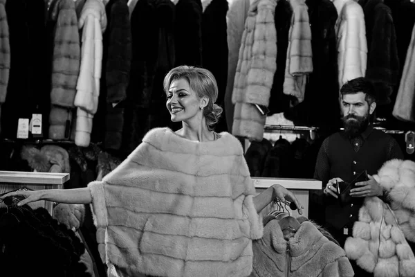 Woman in pink coat with bearded man in fur shop.