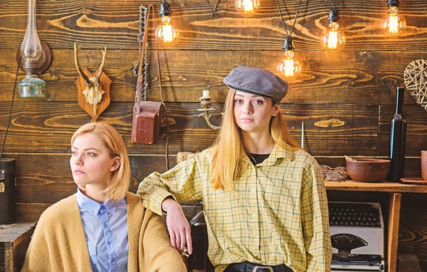 Amigos o hermanas pasan una agradable velada en la casa de guardabosques, fondo interior. Las chicas disfrutan las vacaciones. Las chicas en caras tranquilas disfrutan de un ambiente cálido mientras descansan. Concepto de vacaciones en bosques — Foto de Stock