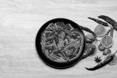 İtalyan makarnası siyah seramik tabakta yemek için malzemeler var.