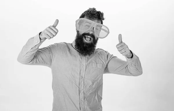 Hipster regardant à travers des lunettes de soleil à rayures géantes. Homme avec barbe et moustache sur le visage heureux porte des lunettes drôles, fond blanc. Optique et concept de lunettes. Le gars à la barbe montre les pouces levés — Photo