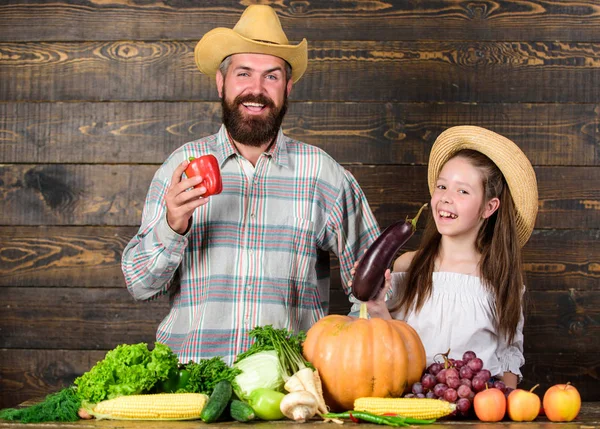 Family father farmer gardener with daughter near harvest vegetables. Farm market with fall harvest. Family farm festival concept. Countryside family lifestyle. Man bearded rustic farmer with kid