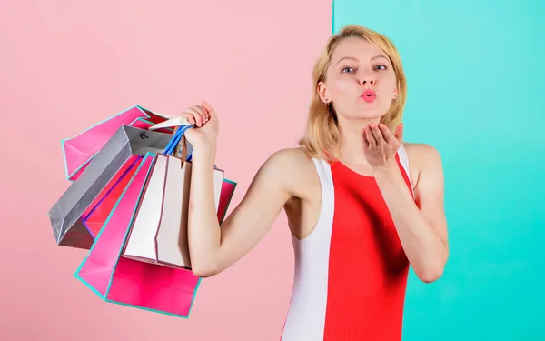 Koop alles wat je wilt. Meisje tevreden met winkelen. Tips om succesvol te winkelen. Meisje houdt van winkelen of net verjaardagscadeaus gekregen. vrouw rood jurk houden bos winkelen tassen blauw roze achtergrond — Stockfoto