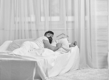 Arka plan üzerinde yatak uyanık, beyaz perde döşeme tişörtlü adam. Uyan ve kavram fazla uyumak. Sabah uyanma sürpriz yüz adam. Sakal ve bıyık maço çağrı uyanık uyuya kalmışım