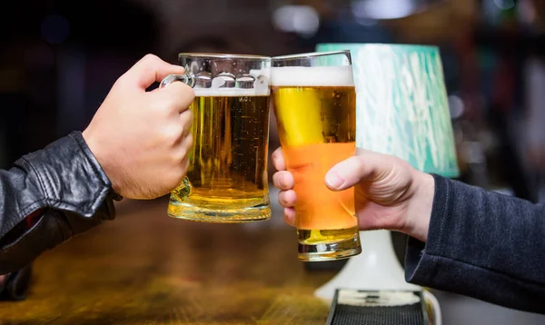 歓声のコンセプトです。泡と新鮮なドラフト ビールとグラス。男性の手が冷たいおいしいビールでいっぱいのマグカップを保持するバーで。金曜日レジャー伝統。バーのカウンターでビール ジョッキ デフォーカス背景 — ストック写真