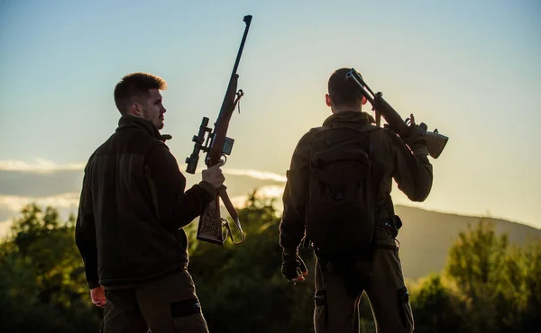 Cazadores amigos guardabosques con armas silueta cielo fondo. Cazadores rifles naturaleza ambiente. Fue un gran día. Termina la temporada de caza. Disfruta de la puesta de sol en las montañas. Cazadores amigos disfrutar del ocio — Foto de Stock