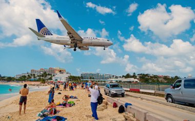 Philipsburg, Sint Maarten - 13 Şubat 2016: uçak arazi maho sahilde insanlar üzerinde. Uçak düşük anında bulutlu mavi gökyüzü. Jet Uçuş deniz üzerinde. Caribbean Beach Tatil. Yolculuk tutkusu, seyahat ve gezi