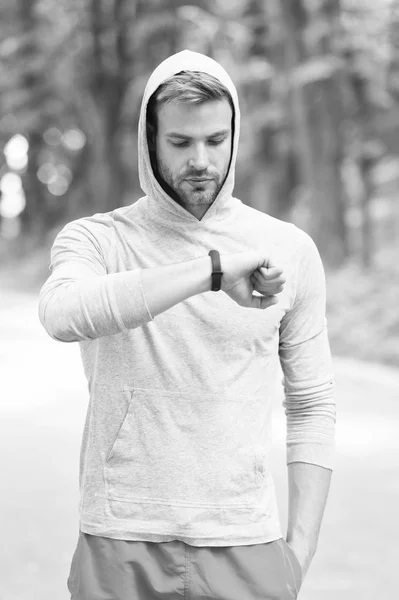 Check time his best score. Man athlete busy face check fitness tracker nature background. Athlete with bristle looks at fitness tracker or pedometer. Sportsman training with pedometer gadget
