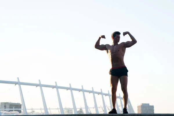 Спортсмен сгибает руки на крыше — стоковое фото