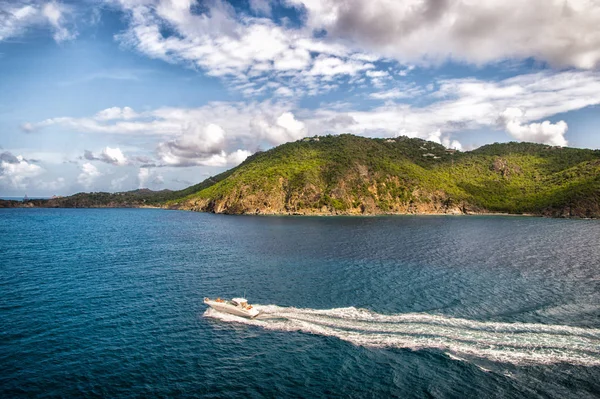 Moottorivene matkustaa sinisellä merellä pilvisellä taivaalla Gustaviassa, St.Barts. Matkustaa laivalla, vaeltaa himo. Kesäloma trooppisella saarella. Vesiliikenne ja laiva. Kaunis maisema vuorilla — kuvapankkivalokuva
