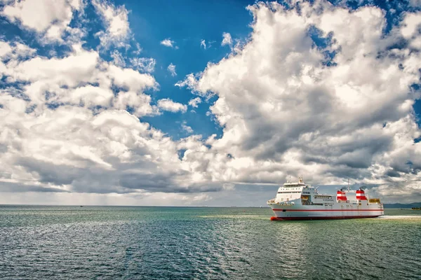 Πλοίο στη θάλασσα στο θολό μπλε του ουρανού. Θαλασσογραφία με υπερωκεάνιο και σύννεφα. Καλοκαιρινές διακοπές, περιπέτεια και περιπλάνησης έννοια. Πλωτές μεταφορές για τη μεταφορά, ταξίδια — Φωτογραφία Αρχείου