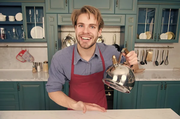 Кухар у блакитній сорочці, червоний фартух посміхається з чайником — стокове фото