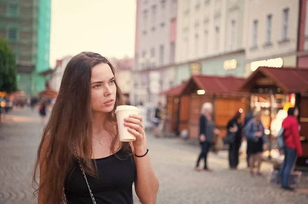 Женщина с выпивкой на вынос ходит по улице. Женщина держит одноразовую чашку кофе. Кофе или чай настроение. Напитки и еда во время летних каникул или путешествий. Девушка с длинными волосами и натуральным макияжем — стоковое фото